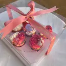 Six Valentine's Day cupcakes in a gift box, tied with pink ribbon.