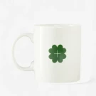 White mug with a green clover and a cross design.