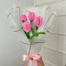 Pink velvet tulips bouquet wrapped in white paper and tied with a pink ribbon.