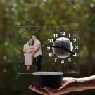 Couple's photo on a clear acrylic clock with LED base, held in a hand.