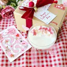 Valentine's Day gift box with candle and board game on red checkered cloth.