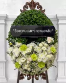 A large, oval wreath of green foliage and white and green flowers with a black banner saying "ข้อความแสดงความอาลัย".