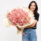 Woman holding a bouquet of pink money flowers with a gold-trimmed wrapper.