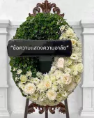 White floral wreath with a black ribbon displaying Thai text for condolences.