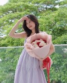 Woman in a striped dress holding a bouquet of pink and red carnations.