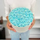 Round white box overflowing with 40 sky blue diamond-studded roses.