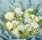 White roses, carnations, lisianthus, and gypsophila in a light blue bouquet with blue wrapping.