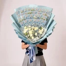 Money bouquet wrapped in blue paper with white flowers, held by a person.
