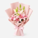 Pink stargazer lilies in a bouquet with pink paper and a pink bow.