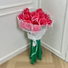 A bouquet of 13 red rose-shaped balloons tied with white ribbon and green balloon stems.