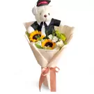 White graduation teddy bear in a bouquet of sunflowers, white flowers, and greenery.