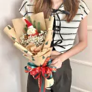 Snowman bouquet with ping pong flowers and a Christmas hat, wrapped in festive paper with a red and green bow.