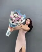 Woman in a pink dress holding a large bouquet of pink and white flowers.