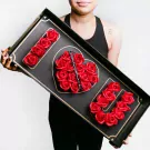 A person holding a black box with "I ♡ U" spelled out in red roses.
