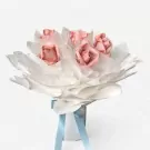 A bouquet of roses made from pink banknotes, wrapped in white tissue paper, tied with light blue ribbon.