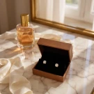 Open jewelry box with two diamond earrings and perfume bottle.