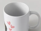 White mug with pink hearts and a dachshund's ear and nose visible.