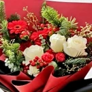 Red and white Christmas bouquet with roses, gerberas, carnations, and pine.