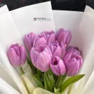 Bouquet of vibrant purple tulips elegantly wrapped in white paper.