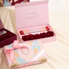Pink gift box with preserved red roses and chocolates, and another pink box with a ribbon.