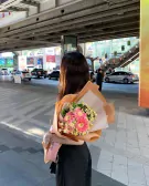 Woman holding a bouquet of pink gerbera daisies and white daisies.