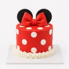 Red polka dot cake with white circles, a large red bow, and black Minnie Mouse ears.