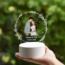 Wedding photo on round acrylic stand with names & date, framed by vines.