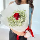Red rose bouquet with white limonium, wrapped in white paper and tied with a red ribbon.