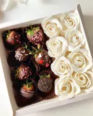 Chocolate-covered strawberries and white roses in a gift box.