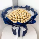 Bouquet of 100 gold-wrapped Ferrero Rocher chocolates in dark blue and white paper, tied with white ribbon.