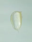A dollop of translucent yellow body wash with small air bubbles on a light blue background.