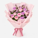 Pink and white roses with purple statice in pink paper with a pink ribbon.
