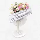 A floral arrangement in a fan shape with a Thai condolence message on a white stand.