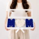 White box holding blue roses and a heart of white roses spelling "MOM".