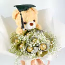 Graduation teddy bear with graduation cap on a bouquet of white flowers and Ferrero Rocher chocolates.