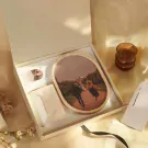 Oval jigsaw puzzle with a couple's photo in an open gift box with a candle.