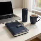 Laptop, notebook, pen, and coffee mug on a desk.