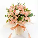 A bouquet of peach and white carnations with eucalyptus, wrapped in pale orange paper and tied with a peach ribbon.