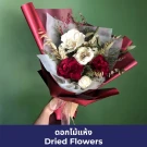 Hand holding a bouquet of dried white and red flowers with red wrapping.