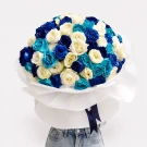 A large bouquet of blue, turquoise, and white roses wrapped in white paper with a dark blue ribbon.