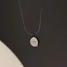Silver necklace with a circular pendant engraved with cursive text and a heart.