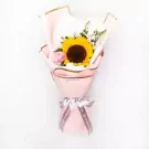 A sunflower and pink carnation bouquet wrapped in pink paper with a silver ribbon.