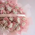 Money bouquet with pink banknotes rolled into cones filled with tiny white flowers.