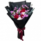 A bouquet of red and white roses with purple statice flowers, wrapped in black paper and tied with a burgundy ribbon.
