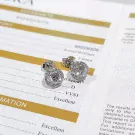 Pair of 0.5-carat round-cut moissanite diamond stud earrings on a certificate.