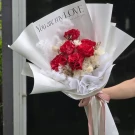 Red roses and white dried flowers in a bouquet with a "You are my LOVE" note.