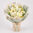 Cream and yellow flowers, including gerberas and roses, in white paper wrapping with a light gold ribbon.
