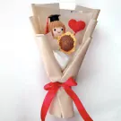 Crocheted graduation doll with sunflower and heart in a bouquet.