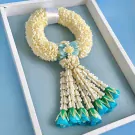 White jasmine garland with light blue flowers and tassels in a white box.