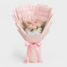 Pink money bouquet with flowers and pink ribbon against a white background.